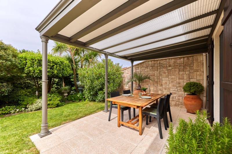 Installation de pergola Luminov colonne rétro avec éclairage LED sous les lames dans un jardin ensoleillé
